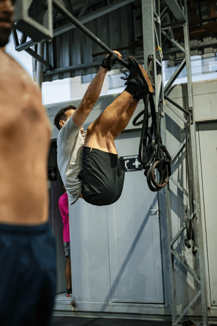 Aluno executa toes-to-bar no rig, com argolas de ginástica ao lado, no CrossFit Canasvieiras em Florianópolis.